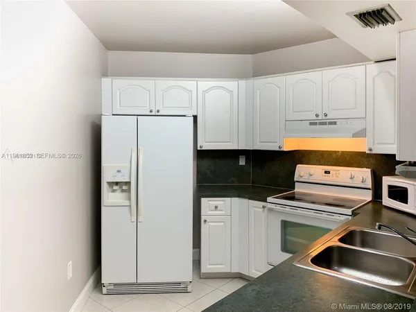 a kitchen with a refrigerator sink and cabinets