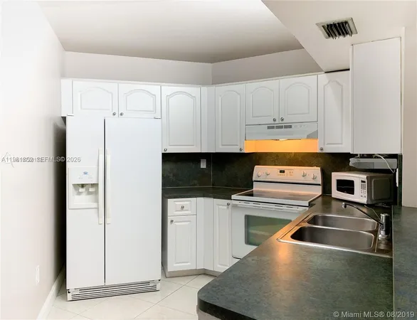 a kitchen with a refrigerator a stove and white cabinets