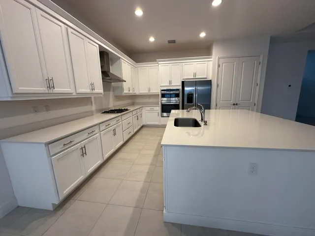 a large kitchen with a refrigerator and a stove top oven