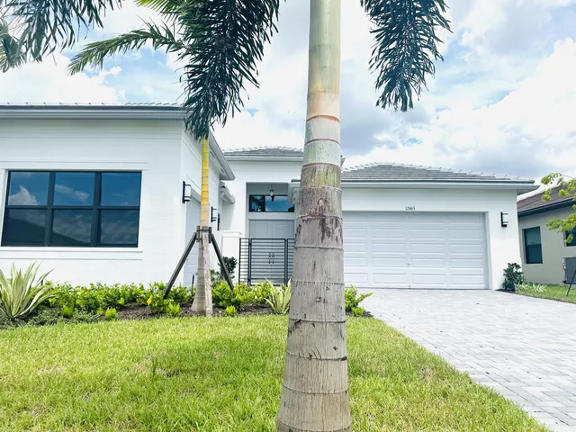 a front view of a house with a yard and palm trees