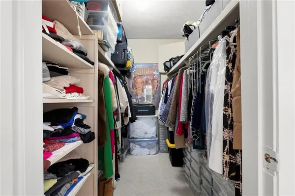 a view of walk in closet with clothes and shoes