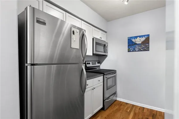 a view of a refrigerator in kitchen and an empty room