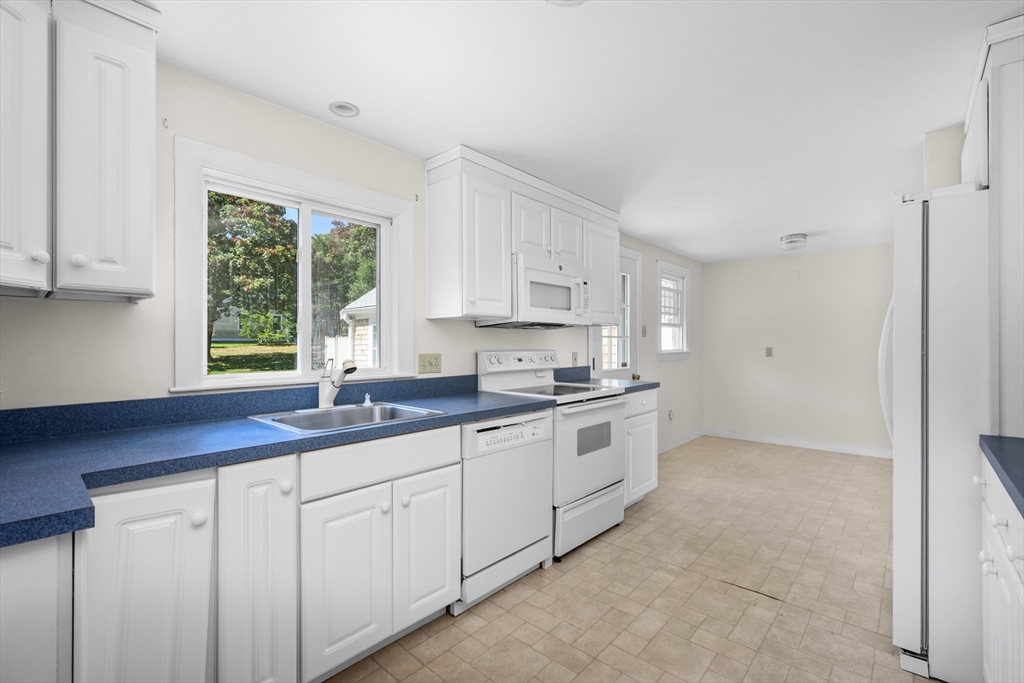 216 Forest Beach Road Chatham, MA 02659 - Photo 7 of 42 a kitchen with granite countertop white cabinets white appliances a sink and a window