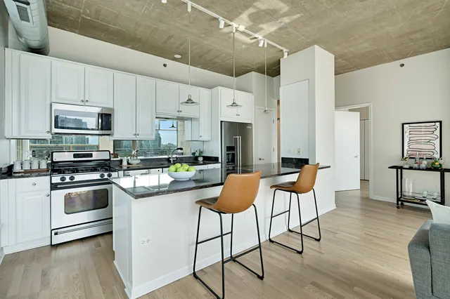 a kitchen with stainless steel appliances kitchen island granite countertop a table chairs stove and white cabinets