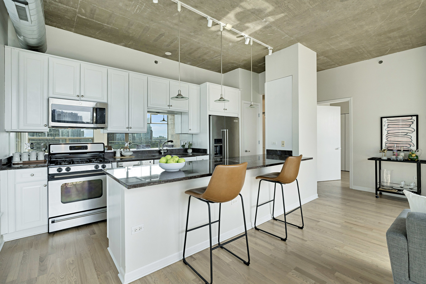 125 East 13th Street, Unit 1213 Chicago, IL 60605 - Photo 6 of 21 a kitchen with stainless steel appliances kitchen island granite countertop a table chairs stove and white cabinets