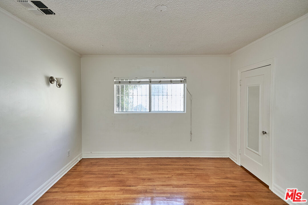 1253 Keniston Avenue Los Angeles, CA 90019 - Photo 17 of 35 a view of an empty room with wooden floor and a window