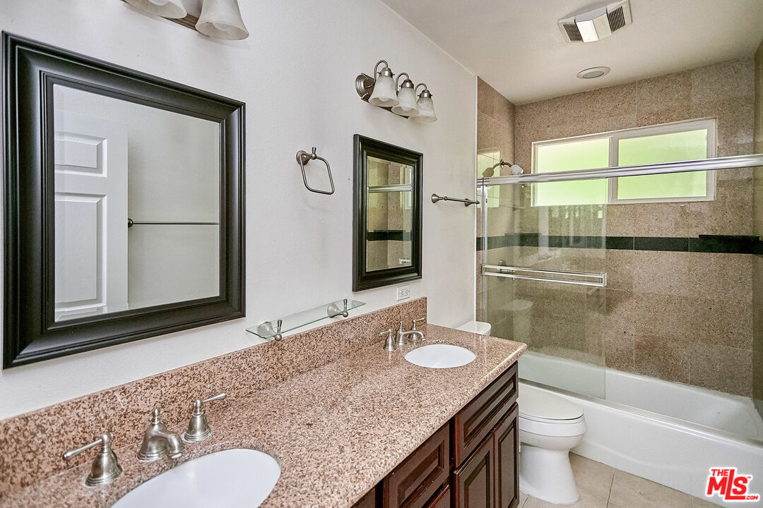 1253 Keniston Avenue Los Angeles, CA 90019 - Photo 18 of 35 a bathroom with a granite countertop sink mirror vanity and toilet