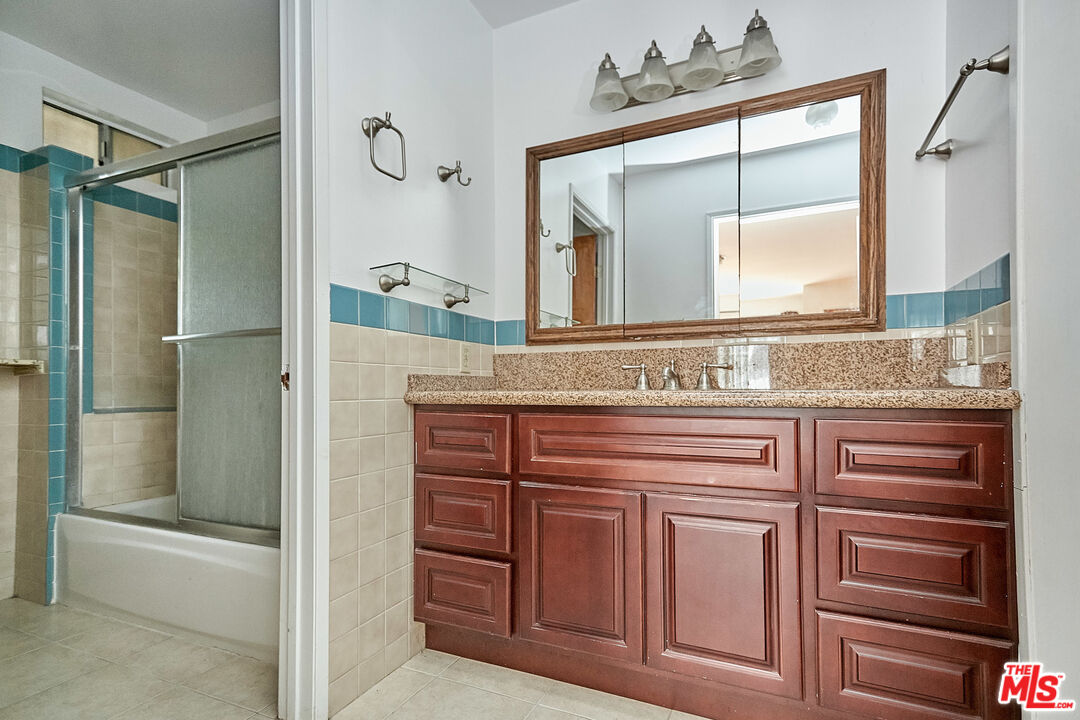 1253 Keniston Avenue Los Angeles, CA 90019 - Photo 24 of 35 a bathroom with a granite countertop sink mirror and a shower