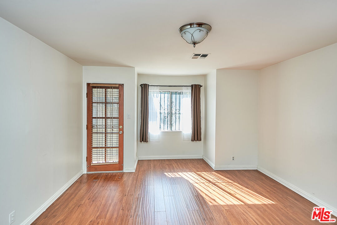 1253 Keniston Avenue Los Angeles, CA 90019 - Photo 27 of 35 an empty room with wooden floor and windows