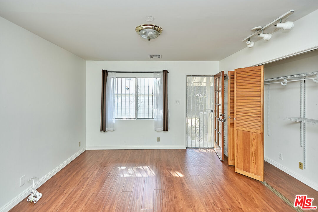 1253 Keniston Avenue Los Angeles, CA 90019 - Photo 28 of 35 an empty room with wooden floor and windows
