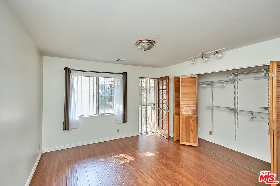 1253 Keniston Avenue Los Angeles, CA 90019 - Photo 29 of 35 an empty room with wooden floor and windows