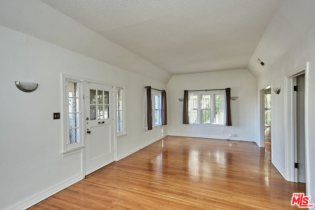 1253 Keniston Avenue Los Angeles, CA 90019 - Photo 3 of 35 a view of an empty room with wooden floor and a window