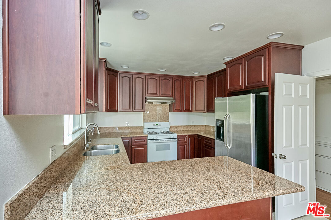 1253 Keniston Avenue Los Angeles, CA 90019 - Photo 32 of 35 a kitchen with a refrigerator sink and wooden cabinets