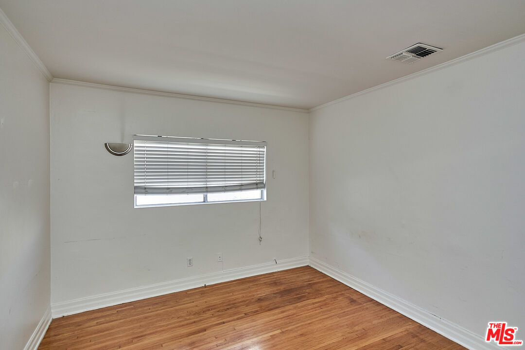 1253 Keniston Avenue Los Angeles, CA 90019 - Photo 6 of 35 a view of an empty room with wooden floor and a window