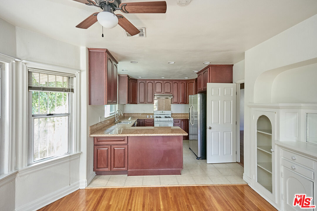 1253 Keniston Avenue Los Angeles, CA 90019 - Photo 9 of 35 a kitchen with a refrigerator a oven and wooden cabinets