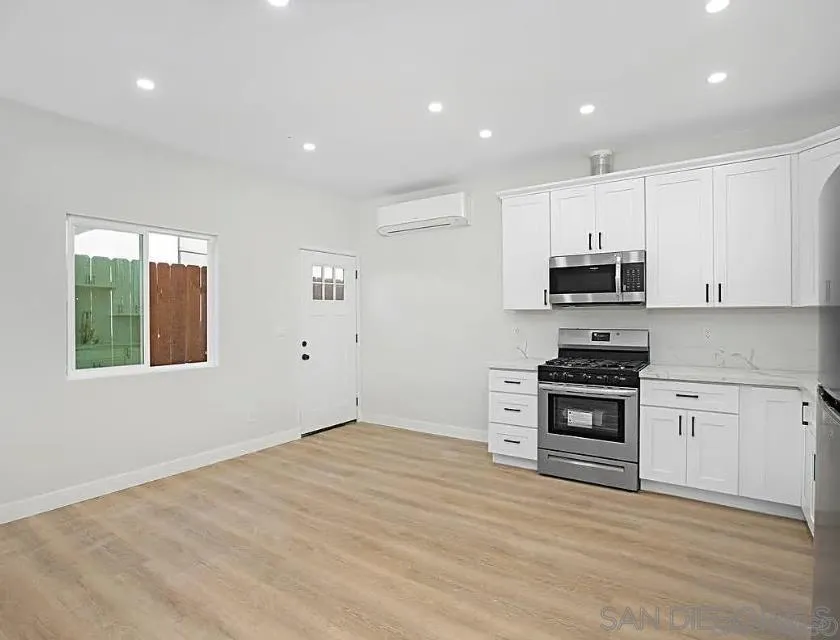 1009 9th Street, Unit 2 Imperial Beach, CA 91932 - Photo 4 of 13 a kitchen with stainless steel appliances a stove top oven a sink a window and white cabinets
