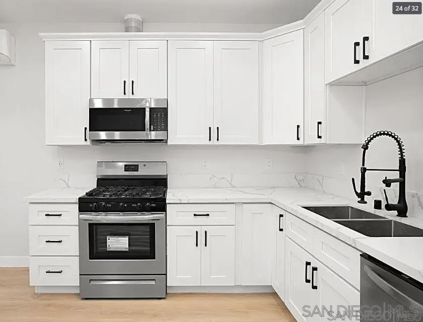 1009 9th Street, Unit 2 Imperial Beach, CA 91932 - Photo 7 of 13 a kitchen with white cabinets and stainless steel appliances