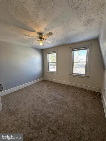 an empty room with windows and ceiling fan