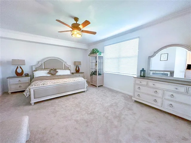 a spacious bedroom with a bed a chandelier and dresser