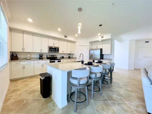 a kitchen with stainless steel appliances kitchen island granite countertop a sink a stove a dining table and chairs