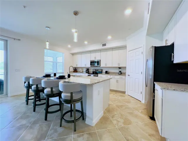a kitchen with a dining table chairs and refrigerator