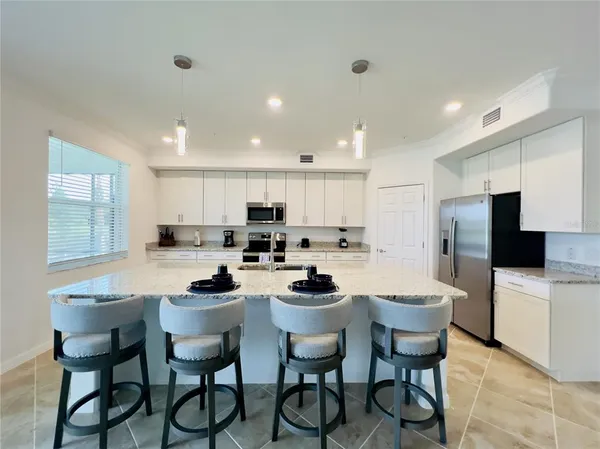 a kitchen with a dining table chairs and refrigerator