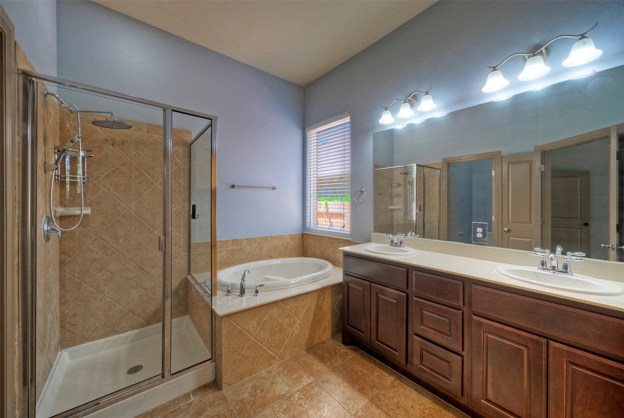1601 Nelson Ranch Loop Cedar Park, TX 78613 - Photo 22 of 30 Warm wood cabinetry and tile finishes surround a glass shower and soaking tub layout.