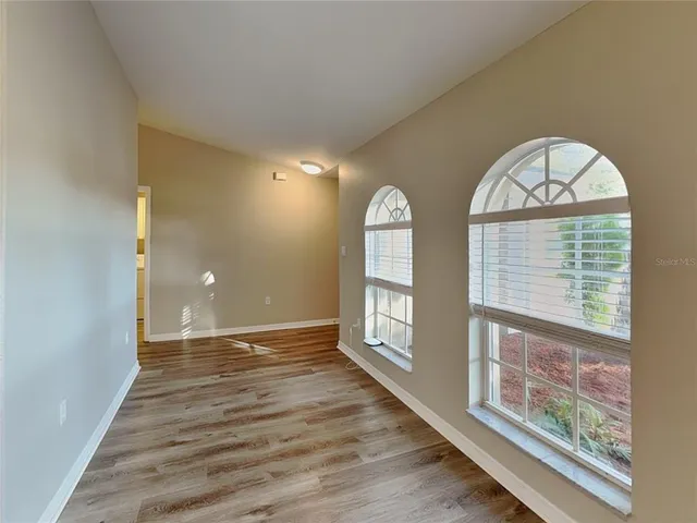 a view of an empty room with a window and wooden floor