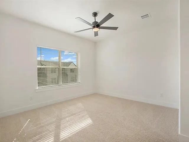 an empty room with ceiling fan and window