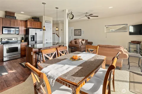a living room with stainless steel appliances furniture a rug and a kitchen view