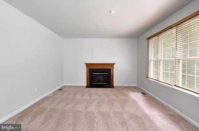 an empty room with a fireplace and large windows