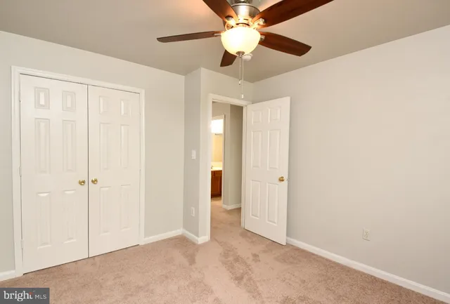 a view of an empty room and chandelier fan