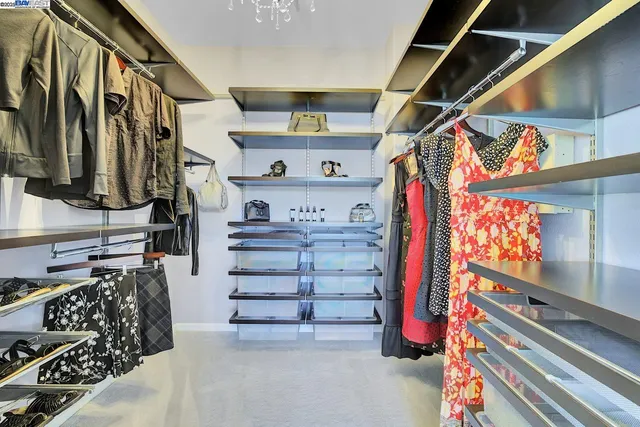 a view of walk in closet with clothes and shoes