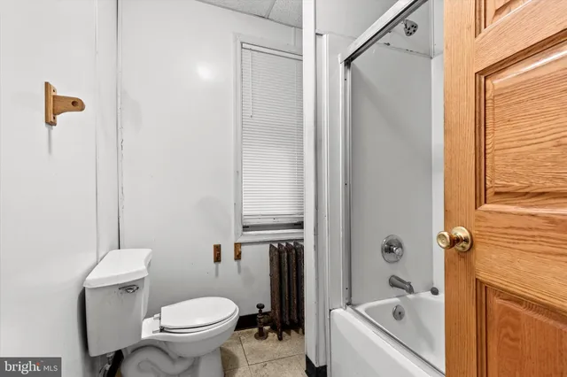 a bathroom with a granite countertop bathtub shower sink vanity and toilet