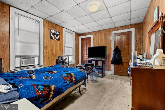 a bedroom with bed and a flat tv screen next to a window