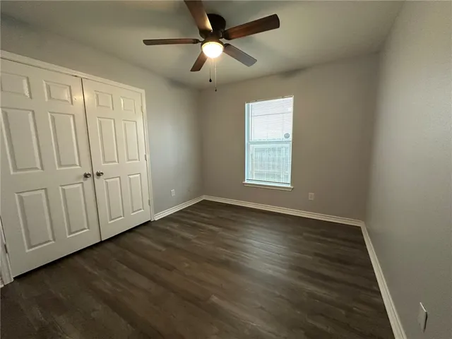 an empty room with wooden floor fan and windows