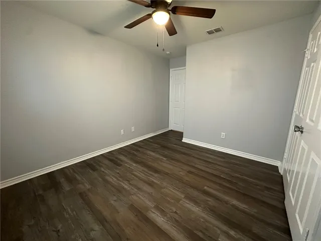 en empty room with wooden floor and ceiling fan