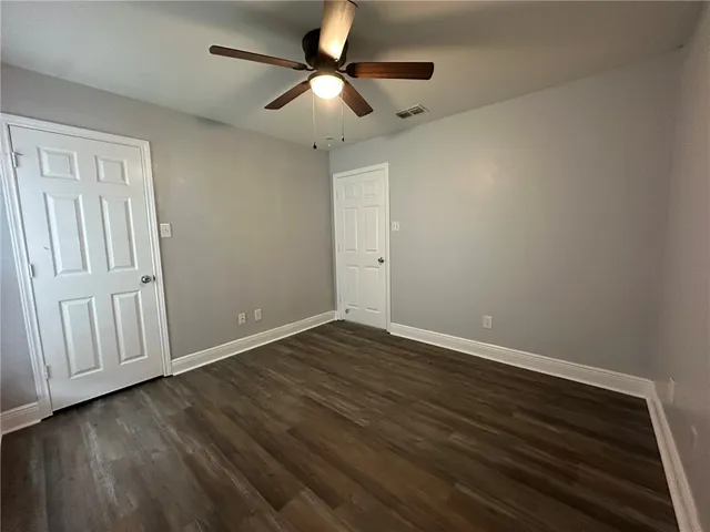 a view of an empty room with wooden floor a ceiling fan