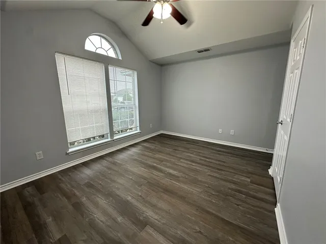 an empty room with wooden floor cabinet and windows