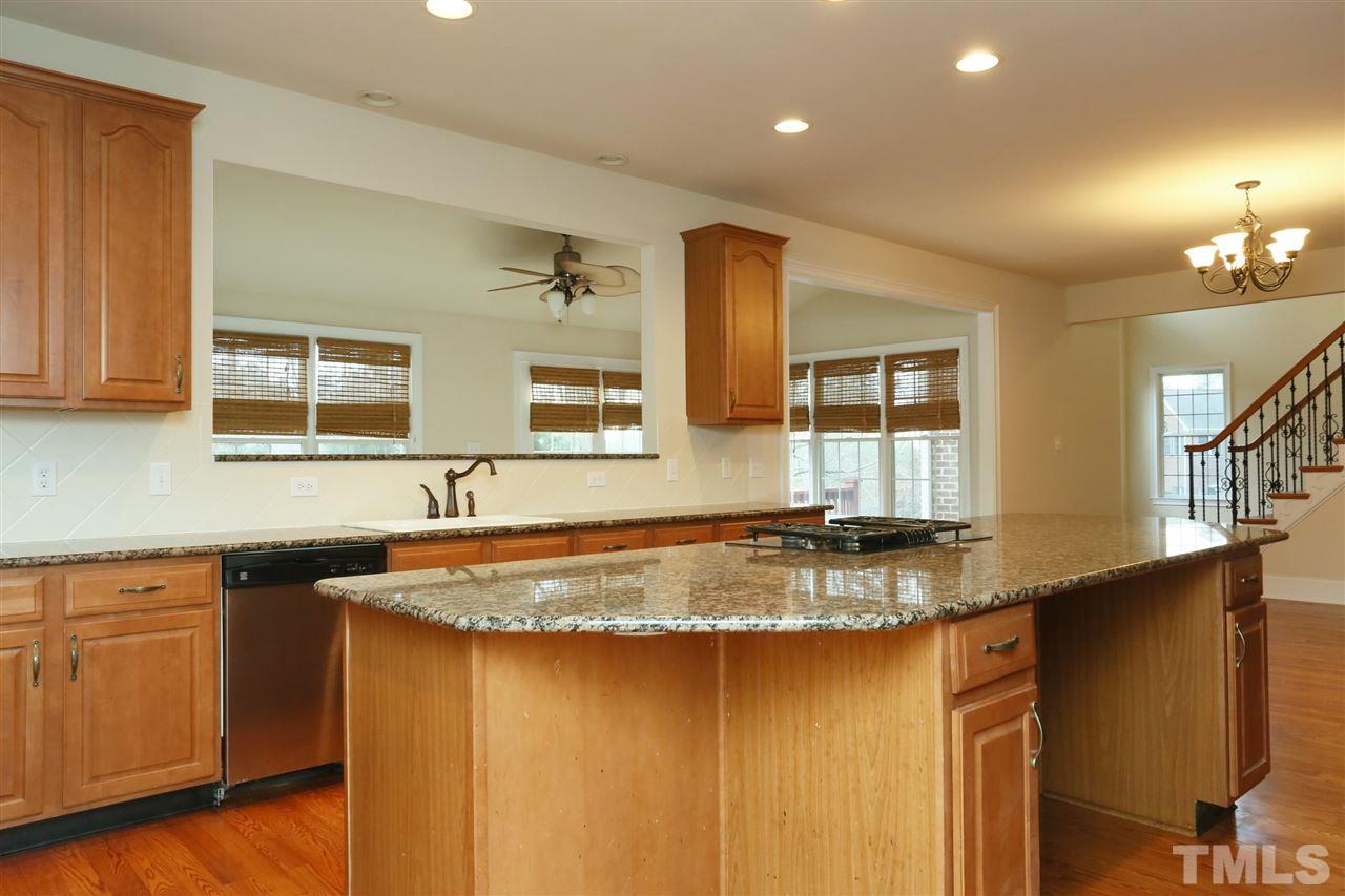 9505 Bluemont Court Raleigh, NC 27617 - Photo 11 of 25 a kitchen with kitchen island granite countertop a sink cabinets and wooden floor