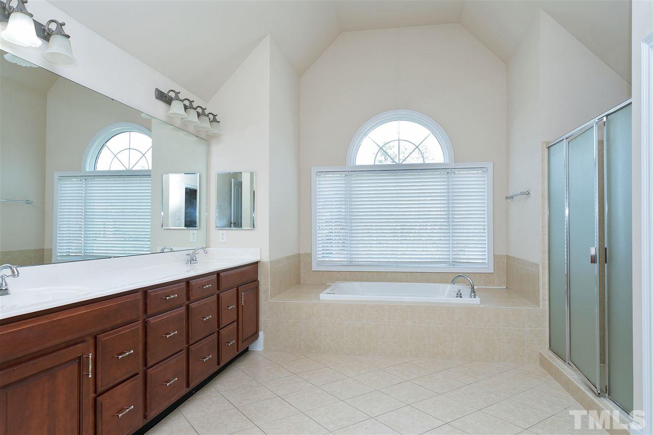 9505 Bluemont Court Raleigh, NC 27617 - Photo 18 of 25 a spacious bathroom with a shower a sink and a mirror