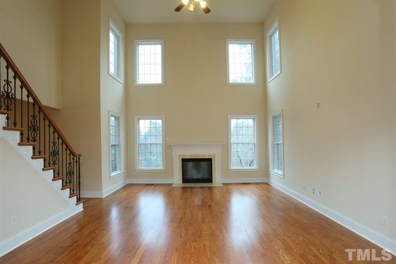 9505 Bluemont Court Raleigh, NC 27617 - Photo 9 of 25 an empty room with wooden floor fireplace and windows