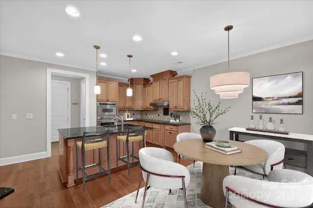 a kitchen with a dining table chairs sink and white cabinets