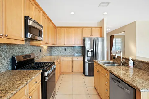a view of an empty room with window and kitchen view