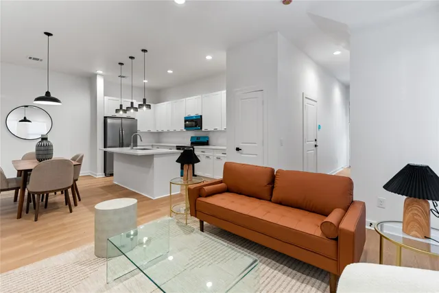 a living room with furniture kitchen view and a chandelier