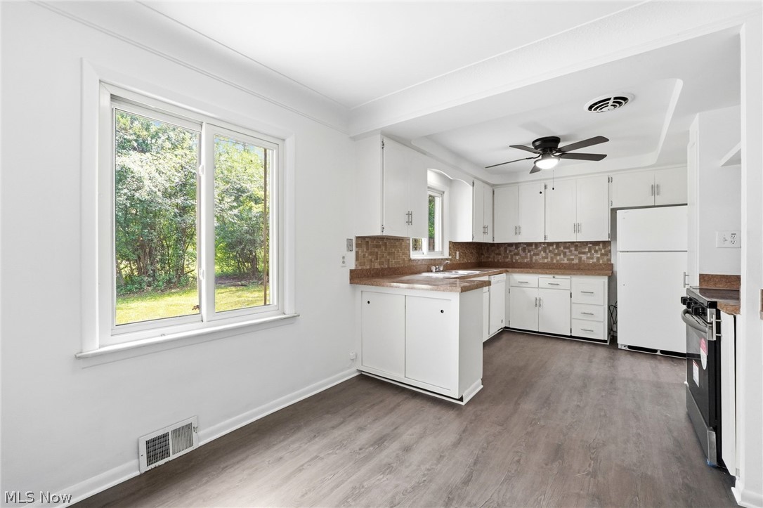 2537 Edgewood Road Beachwood, OH 44122 - Photo 16 of 39 Open-concept kitchen and dining area featuring wood-finish flooring, white cabinetry, integrated appliances, and a mosaic tile backsplash