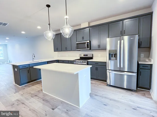 a kitchen with kitchen island a sink stainless steel appliances and cabinets