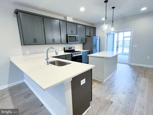 a kitchen with stainless steel appliances a sink stove and wooden floor