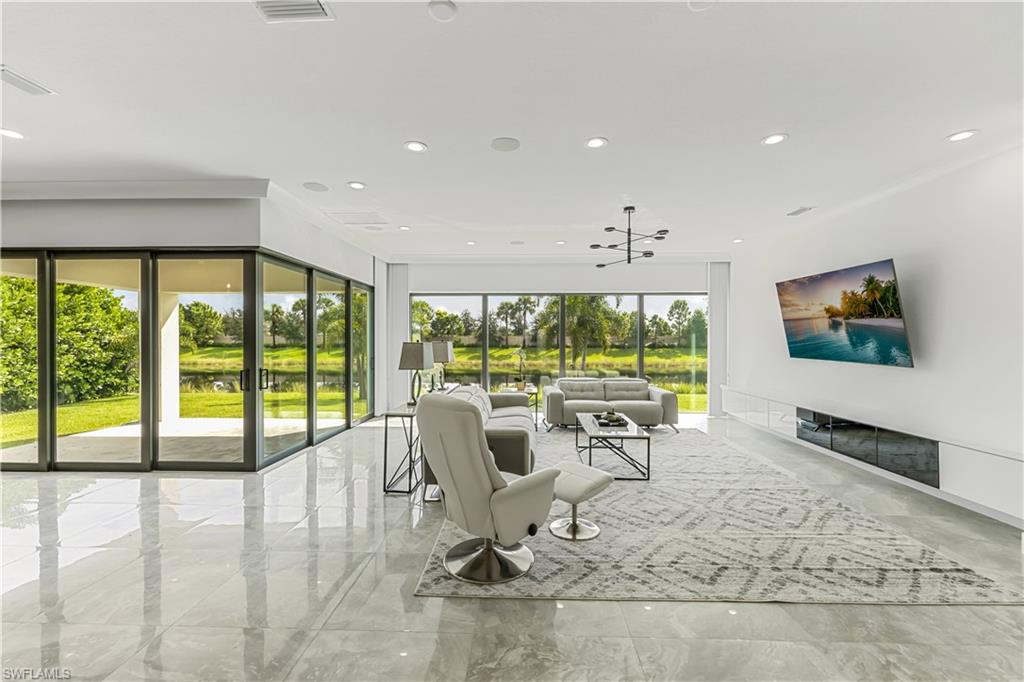 4410 Caldera Circle Naples, FL 34119 - Photo 14 of 30 a living room with large windows and a flat screen tv
