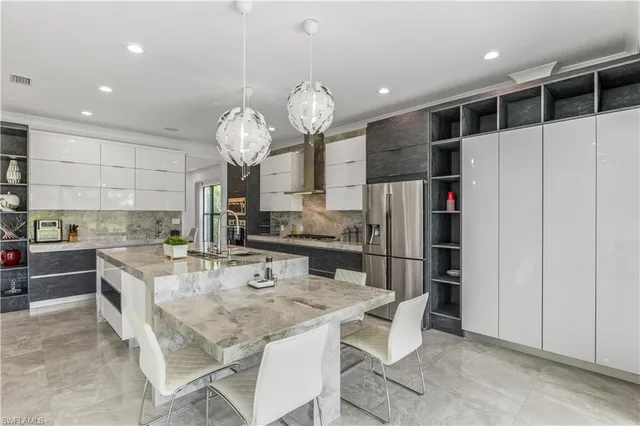 a kitchen with stainless steel appliances kitchen island granite countertop a refrigerator a stove top oven a sink and dishwasher